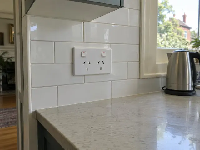 White double power point on a tiled kitchen splashback above a stone countertop in Kirribilli